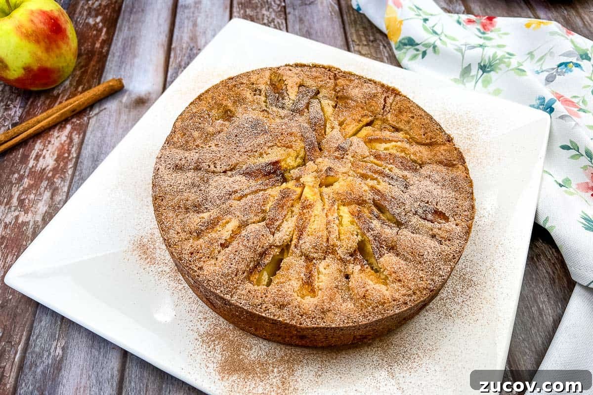 33 Irresistible Fall Desserts That Defy Portion Control 13 An apple cake on a white plate with cinnamon sticks.