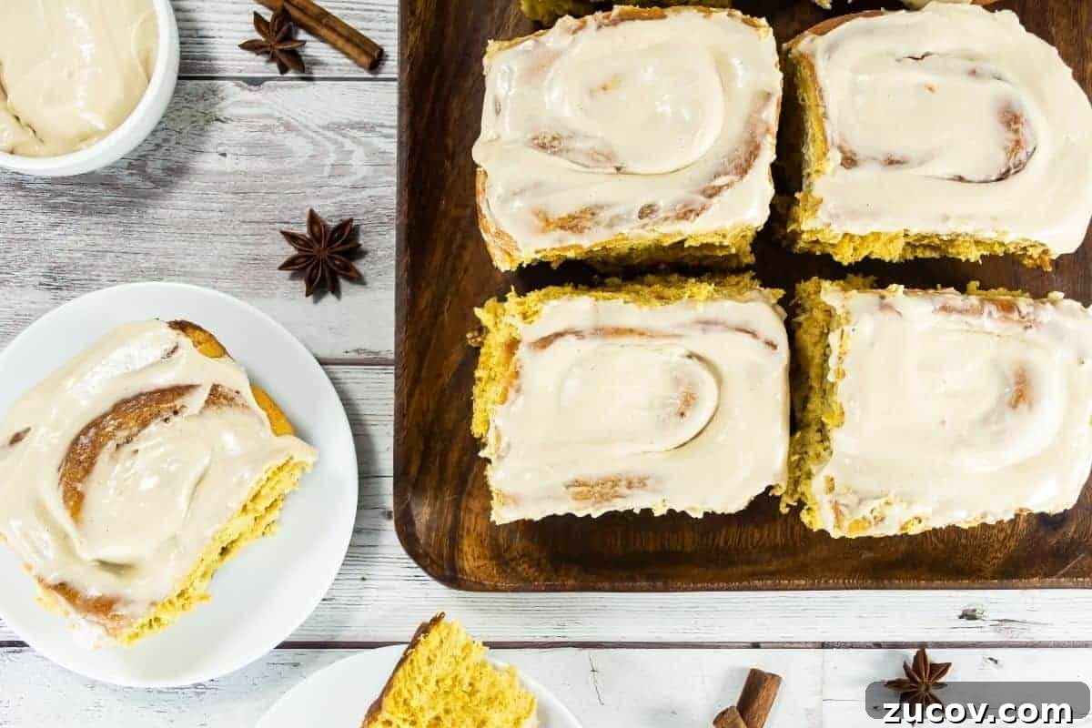 33 Irresistible Fall Desserts That Defy Portion Control 14 Four pumpkin cinnamon rolls are on a wooden board, with one roll served on a white plate.