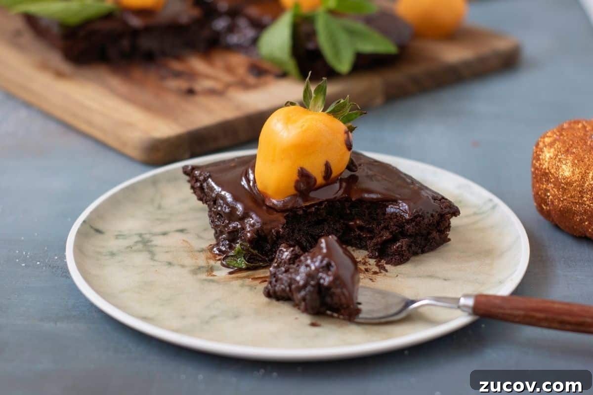 33 Irresistible Fall Desserts That Defy Portion Control 19 A piece of Pumpkin Patch Brownie Cake. sits on a plate with a fork. More cake is visible in the background on a wooden board.