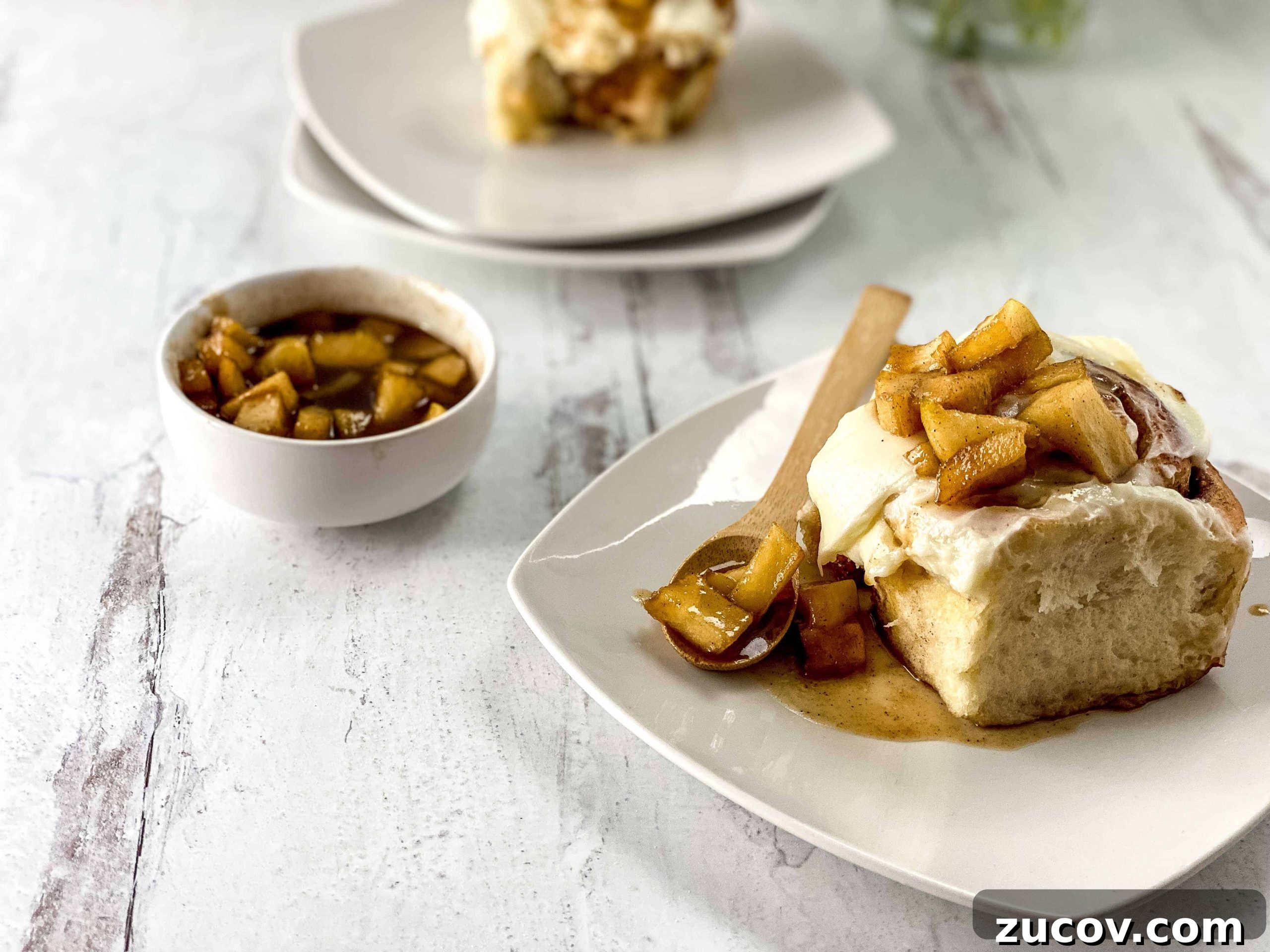 33 Irresistible Fall Desserts That Defy Portion Control 24 An apple cinnamon roll on a plate with a spoon.