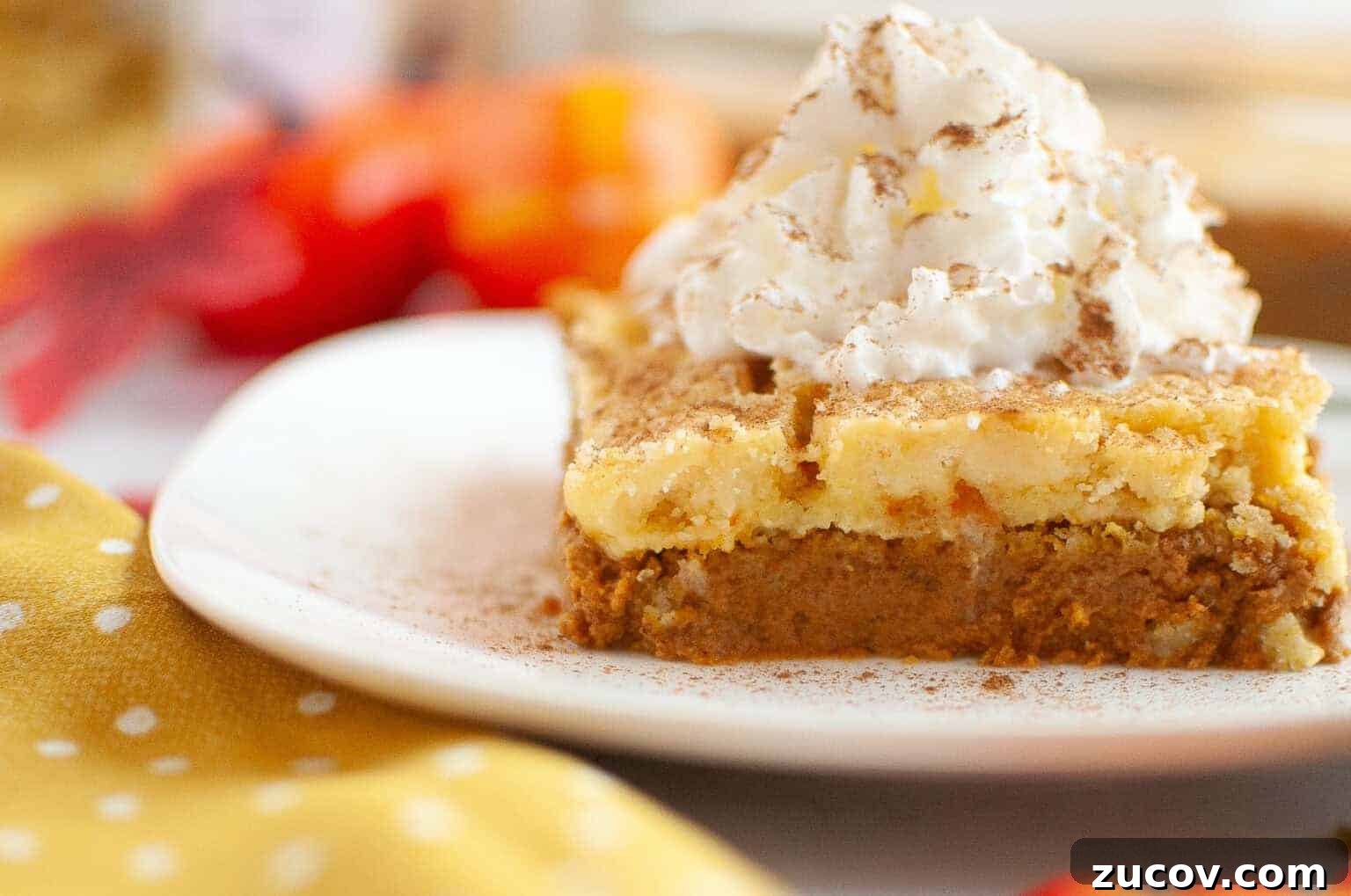 33 Irresistible Fall Desserts That Defy Portion Control 34 A slice of layered pumpkin dessert topped with whipped cream and a sprinkle of cinnamon on a white plate.