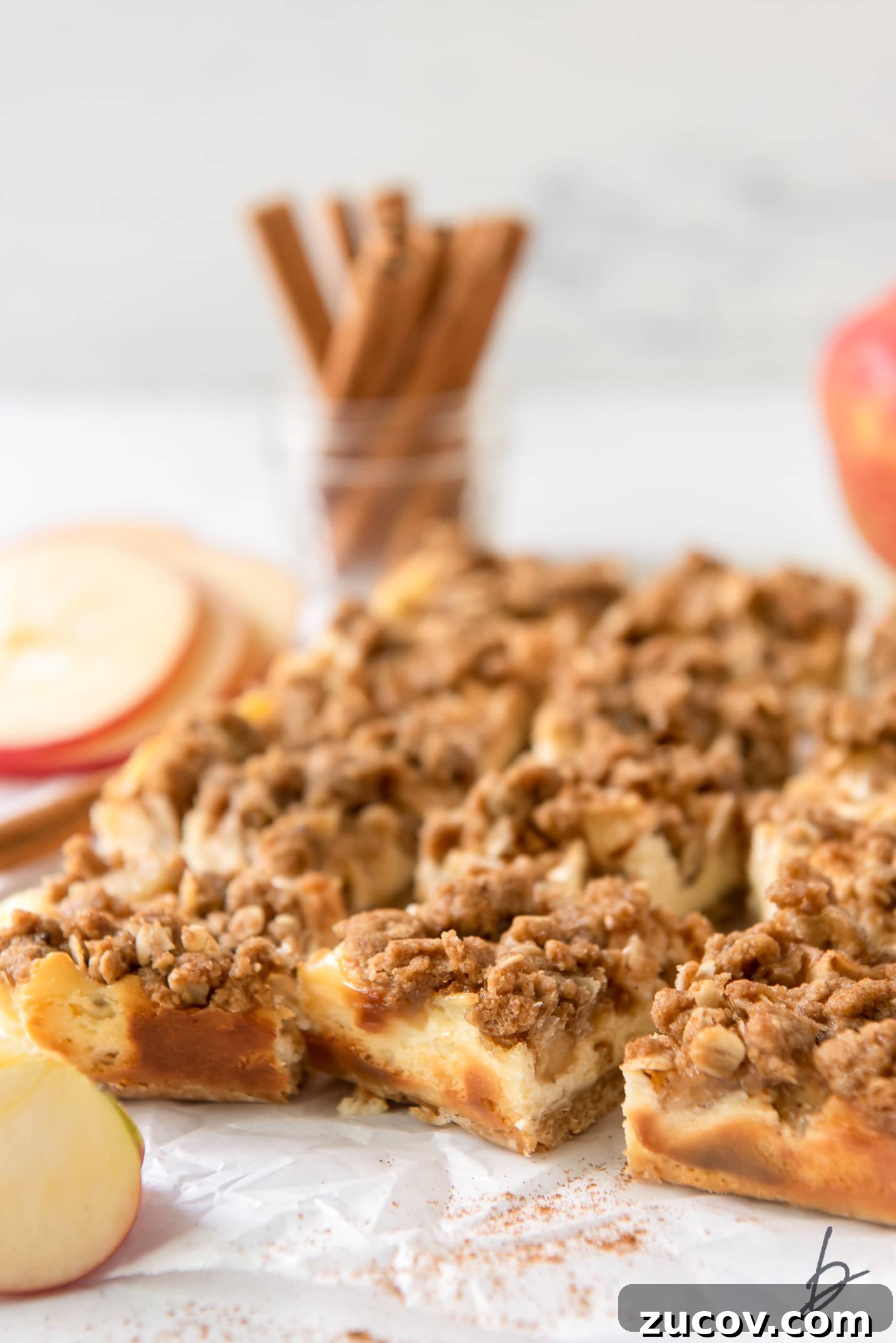 Apple Cheesecake Bars Recipe with Cinnamon Streusel 6 apple cheesecake bars with streusel on parchment paper