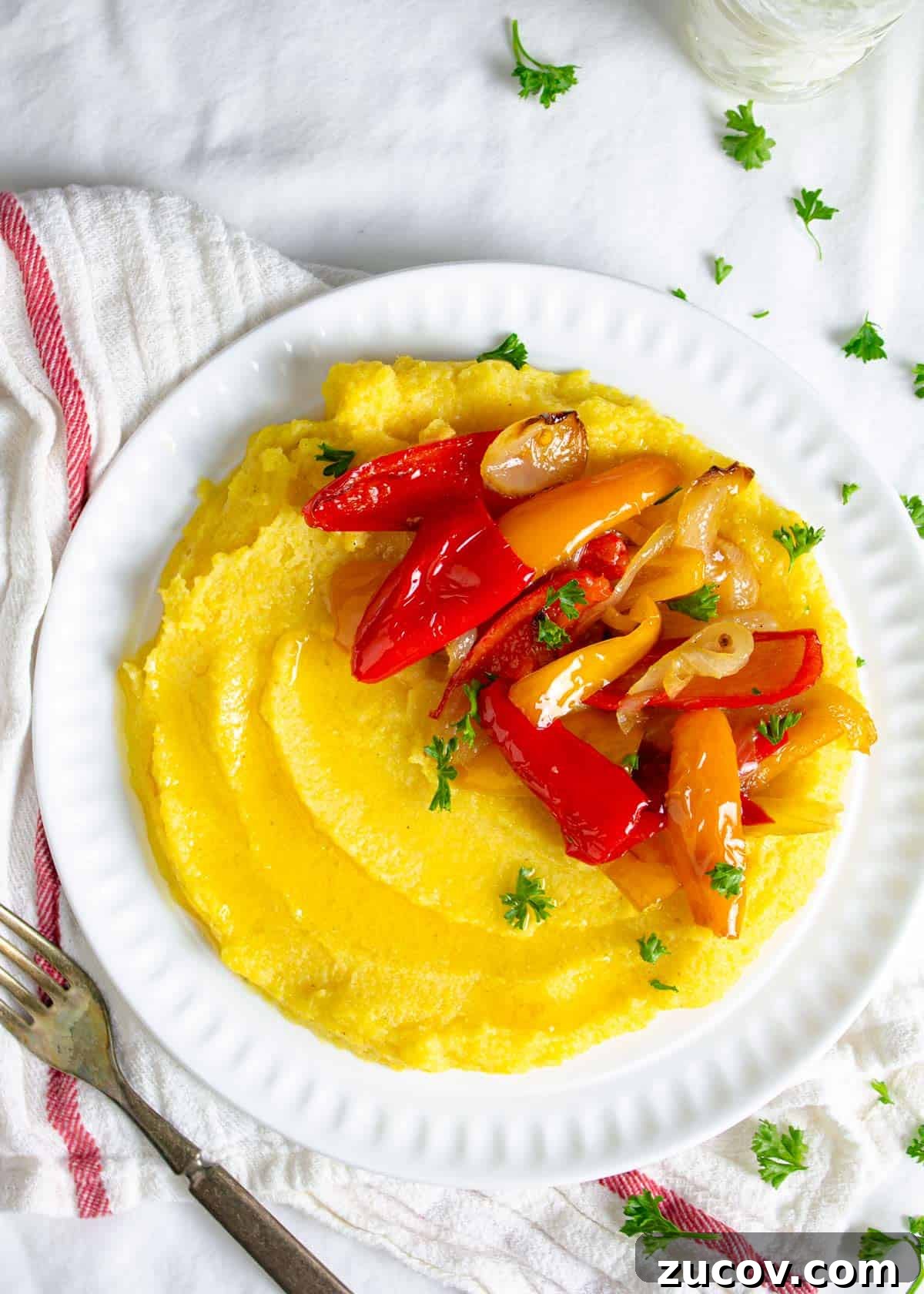 Creamy Polenta with Caramelized Onions and Sautéed Peppers 2 Boiled cornmeal porridge on a plate with roasted peppers and onions.