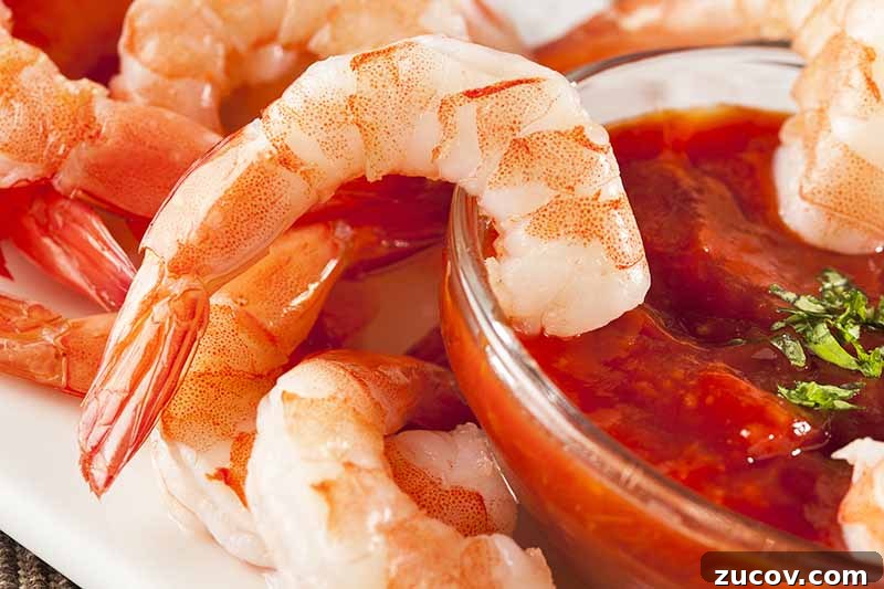 Prawns vs Shrimp: Key Differences, Uses, and How to Tell Them Apart 7 Horizontal image of dipping boiled shrimp in cocktail sauce.