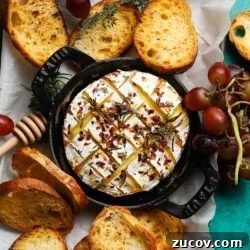 Baked Camembert with Honey & Chili Flakes Recipe 8 Baked camembert topped with honey and chili flakes, surrounded by toasted bread and grapes.