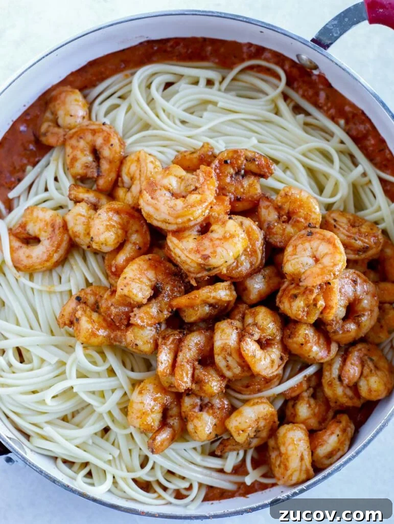 Creamy Spicy Shrimp Pasta with Garlic and Chili Oil 4 Shrimp on top of noodles in a skillet.