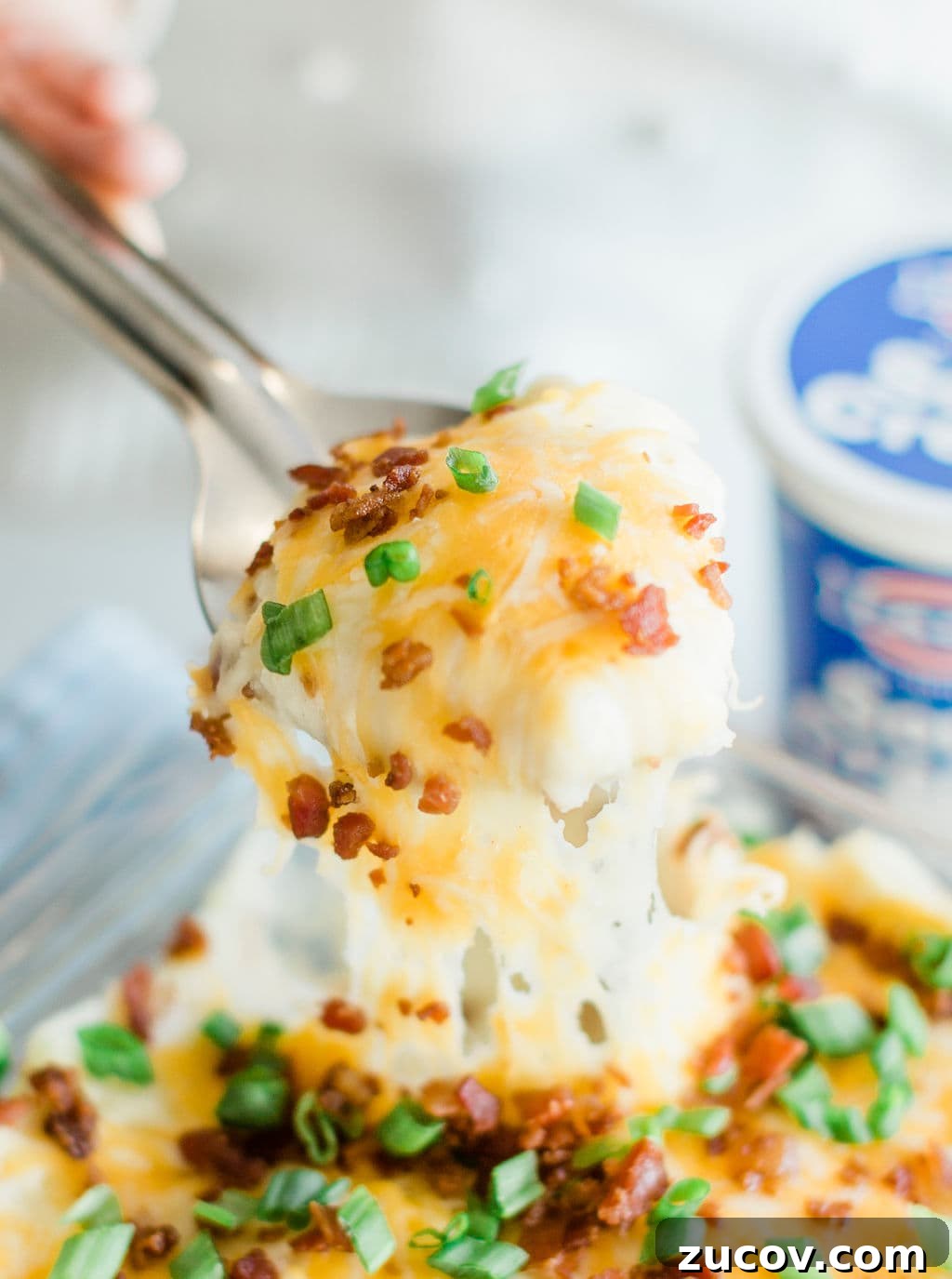 Creamy Loaded Mashed Potato Casserole with Bacon and Cheddar 3 Mashed potatoes with hot melted cheese, green onions and bacon on spoon