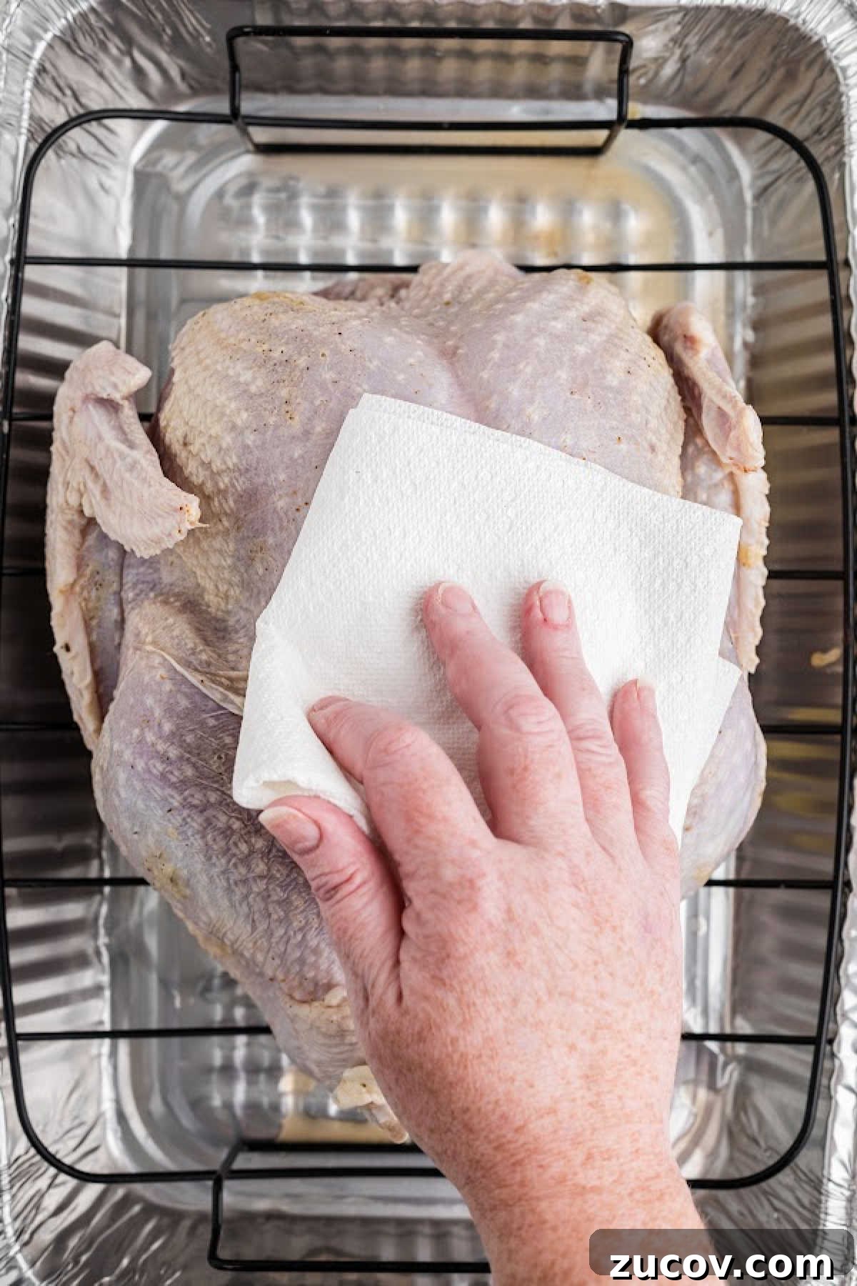 Savory Smoked Turkey Rub Recipe for Bold, Crispy Flavor 5 A hand patting a turkey dry with a paper towel.