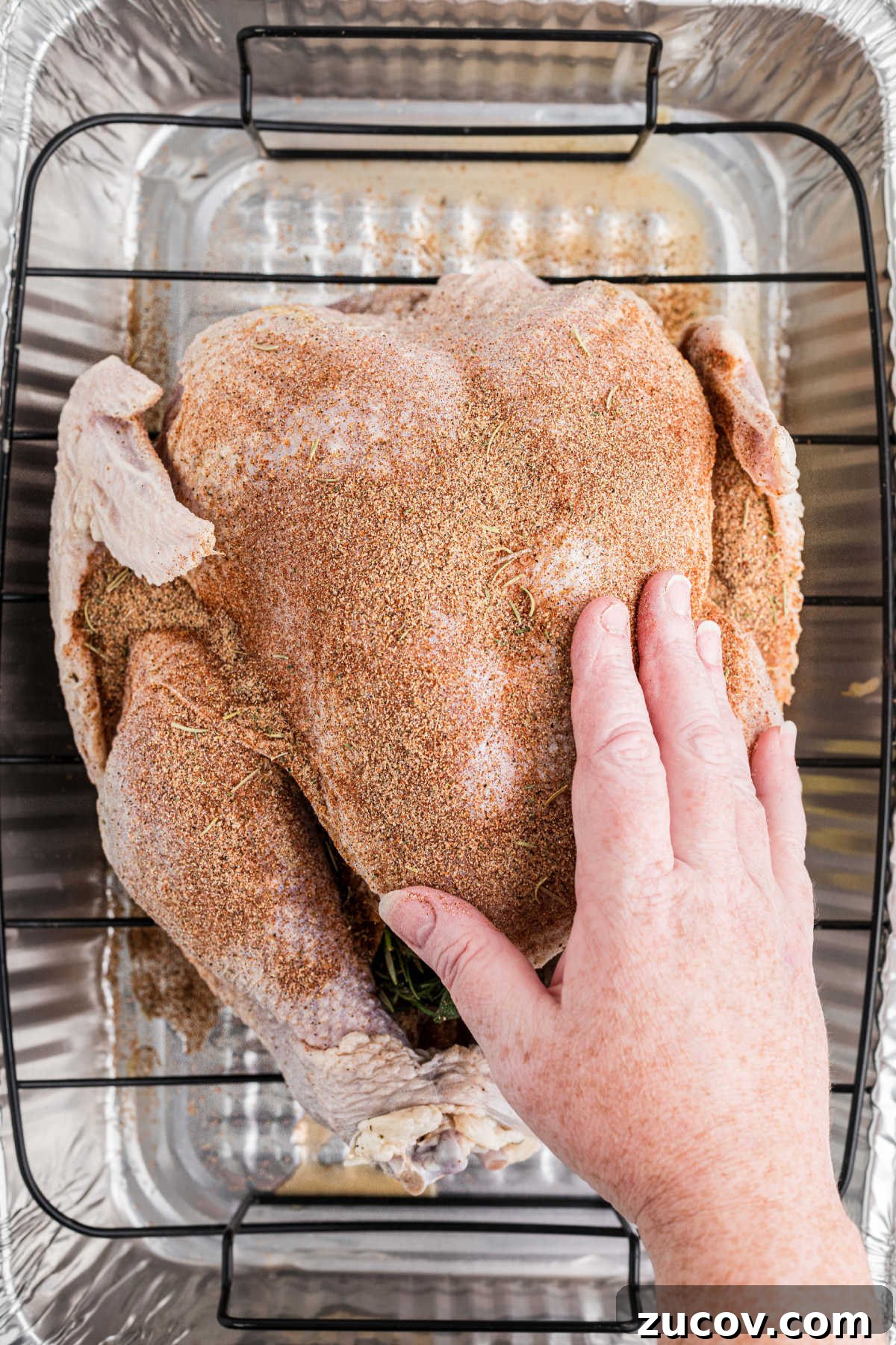 Savory Smoked Turkey Rub Recipe for Bold, Crispy Flavor 6 A hand rubbing a seasoning mix over a turkey.