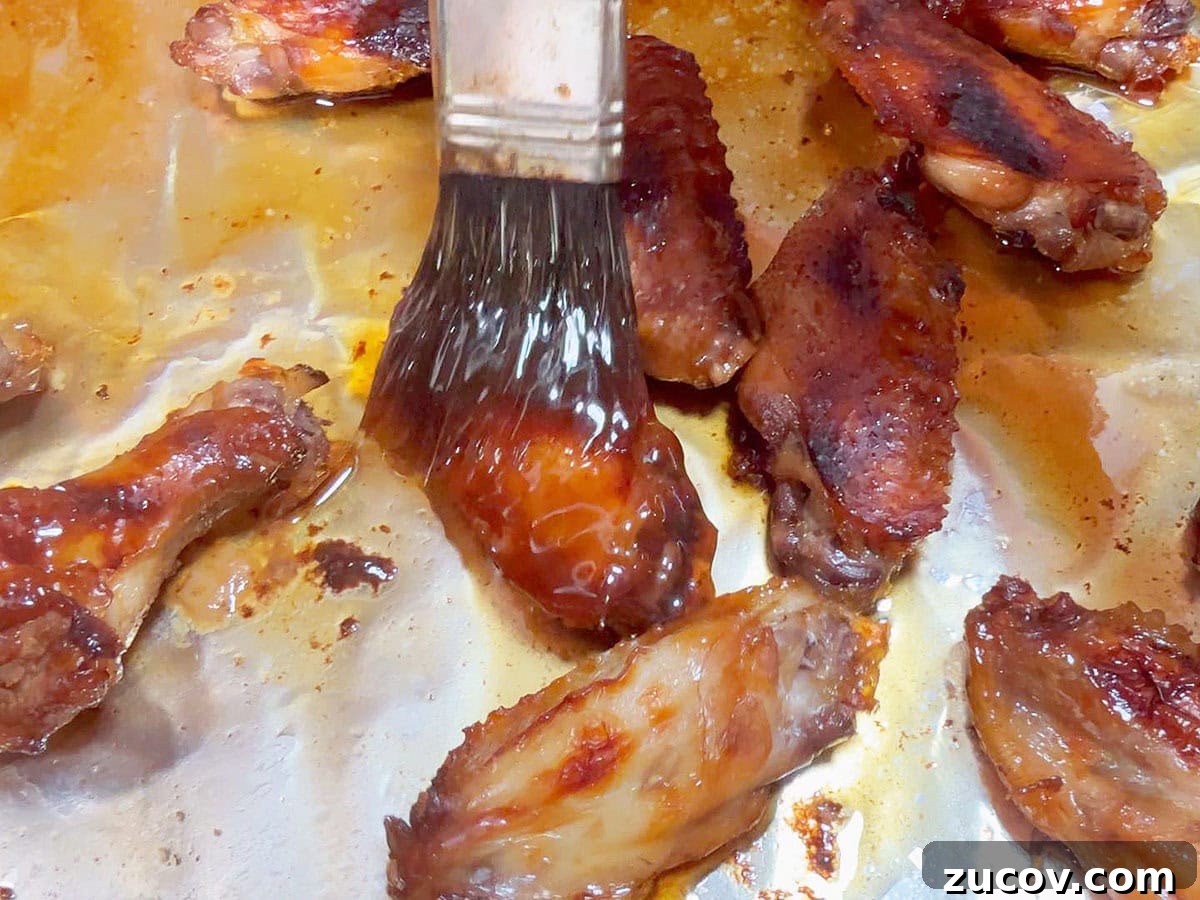 Sticky Honey Garlic Chicken Wings Recipe for Crispy Oven-Baked Wings 8 Brushing the reserved honey garlic sauce on cooked chicken wings.