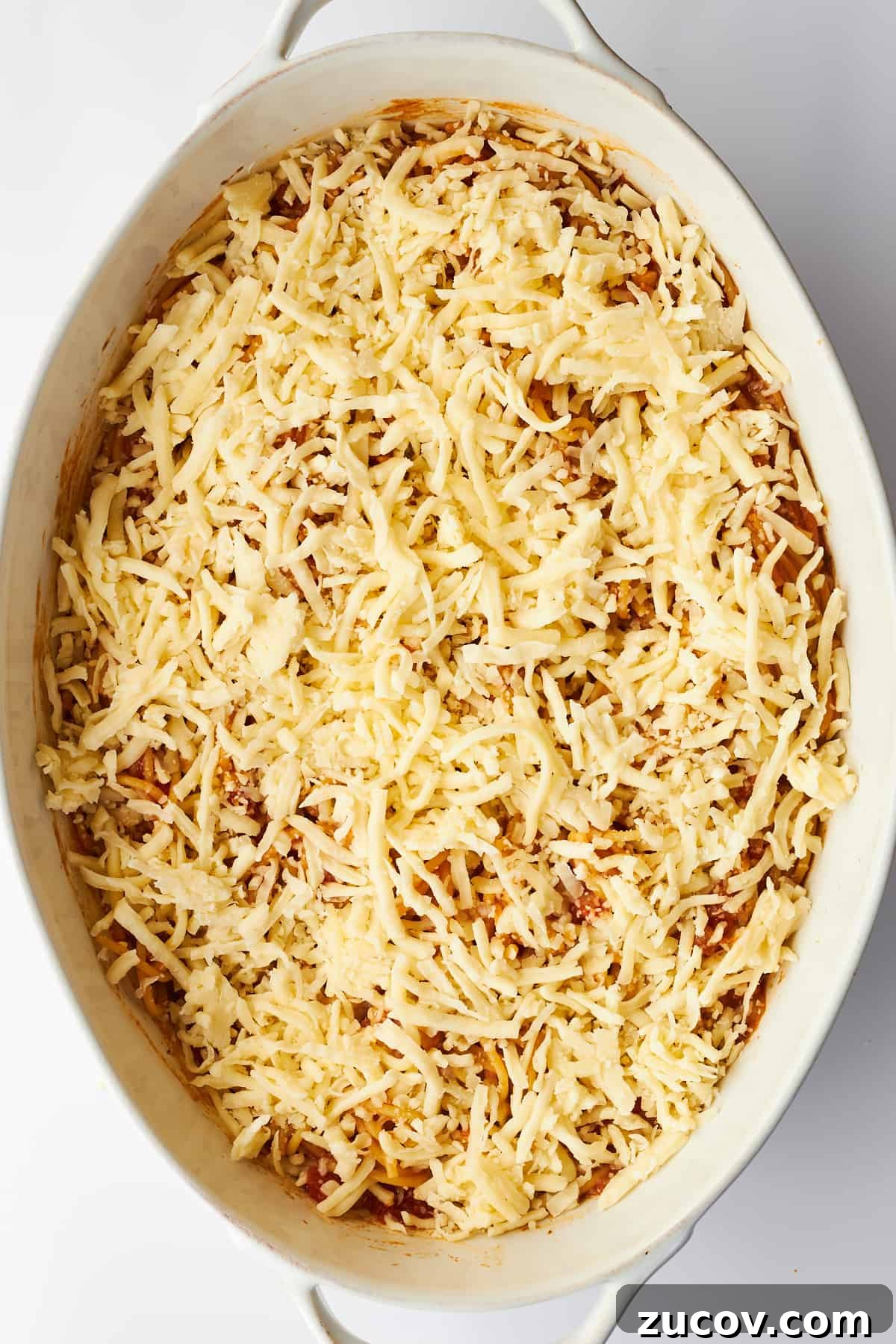 Cheesy Oven-Baked Spaghetti Casserole Recipe 9 Cheese sprinkled over baked spaghetti in an oval dish.