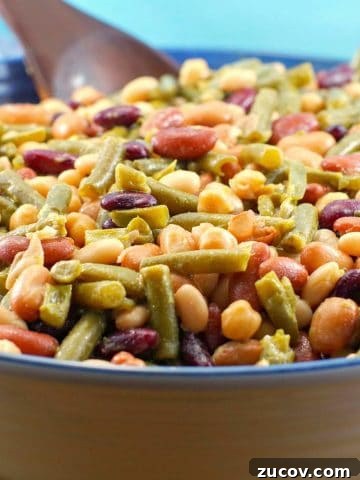 Easy (vegan) mixed bean salad in a large bowl with a dark brown wooden spoon