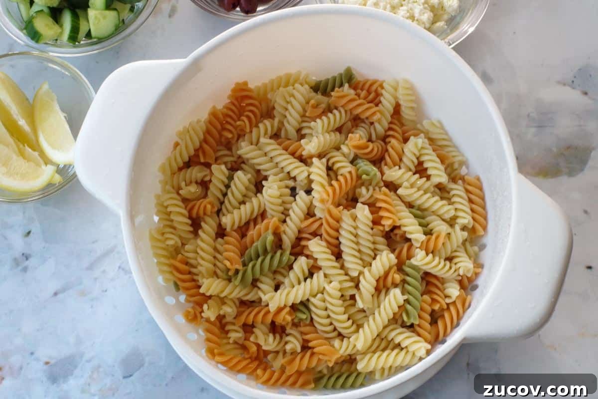 Greek Pasta Salad for Potlucks: Fresh Mediterranean Recipe 6 Cooked and drained pasta in a colander.