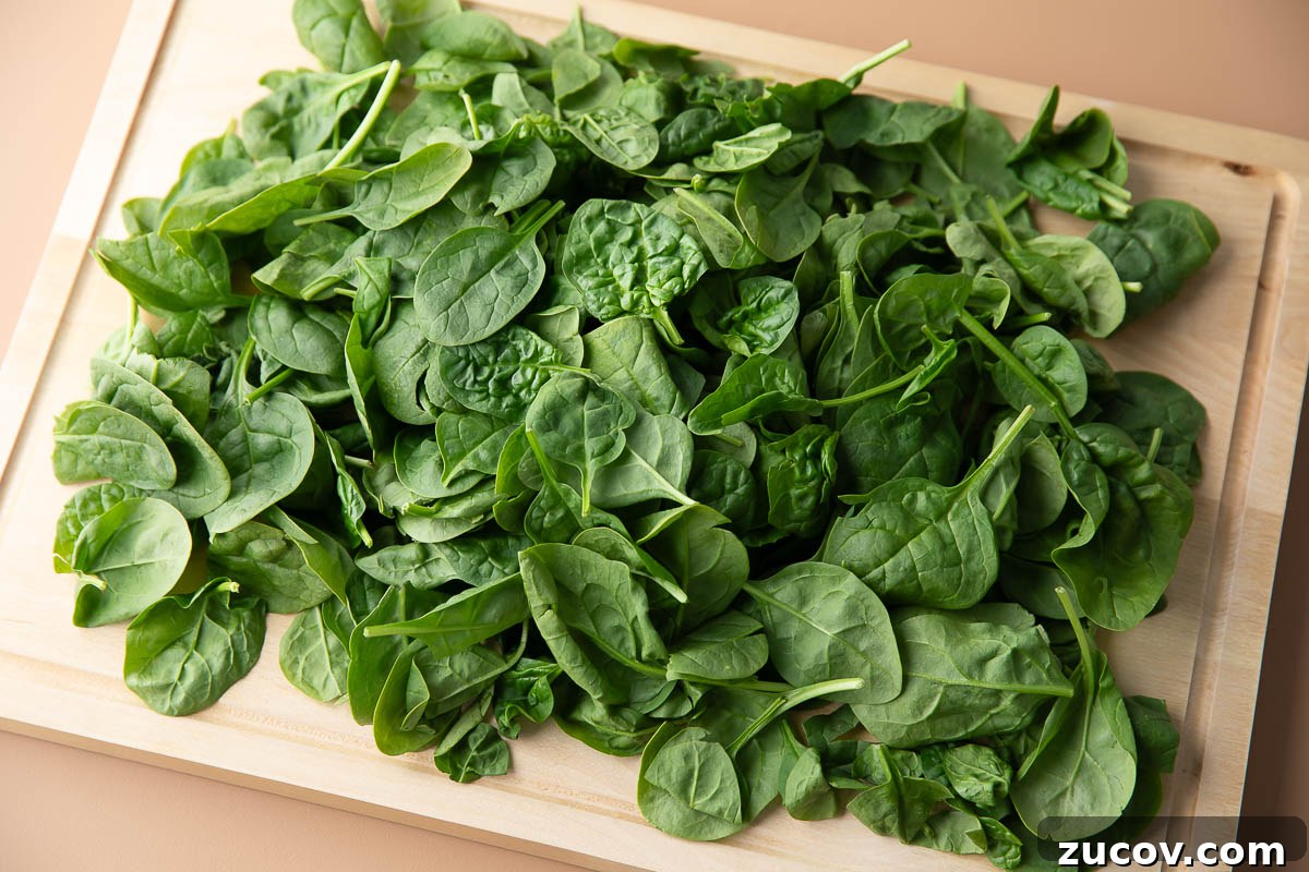 Silky Creamed Spinach Recipe: Quick Side Dish for Any Meal 3 fresh baby spinach leaves on a wooden cutting board