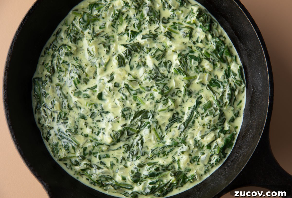 Silky Creamed Spinach Recipe: Quick Side Dish for Any Meal 6 cream cheese creamed spinach with garlic and onion in a cast iron skillet