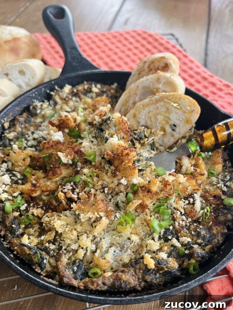 Creamy Baked Crab and Spinach Dip for Parties and Game Day 2 Creamy baked spinach and crab dip in cast iron pan with baguette slices and spoon over baking rack.