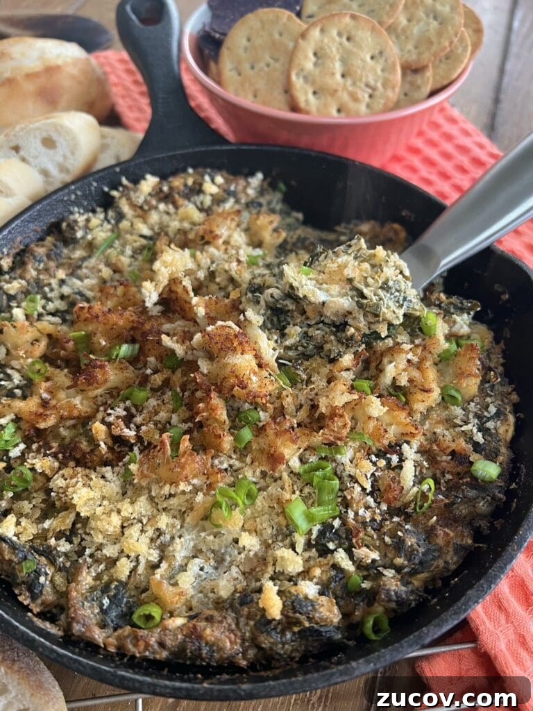 Creamy Baked Crab and Spinach Dip for Parties and Game Day 11 Creamy baked crab and spinach dip in cast iron pan with baguette slices and spoon over baking rack.