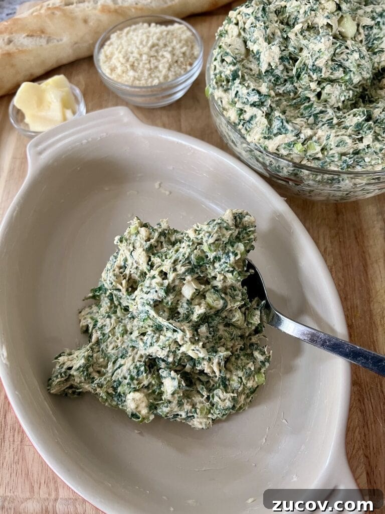 Creamy Baked Crab and Spinach Dip for Parties and Game Day 7 Spooning the crab spinach dip mixture into butterred casserole dish.