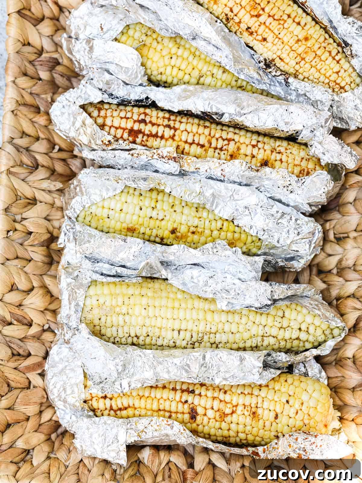 Authentic Mexican Street Corn (Elotes) — Classic Recipe Guide 9 A larger serving basket with Grilled Corn unwrapped in foil laying in the basket before eating.