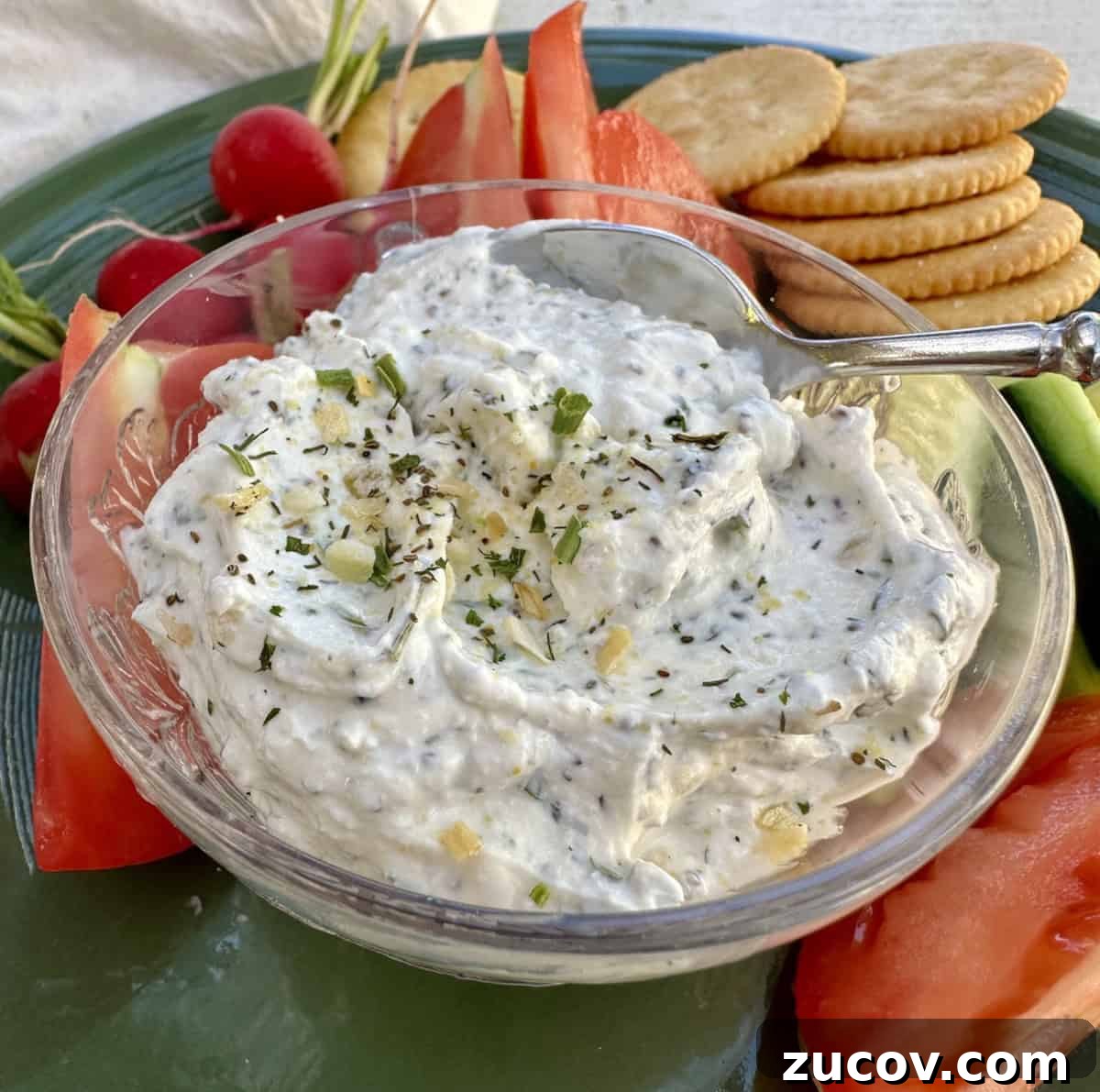 Creamy Herb and Garlic Dip Recipe for Parties and Snacks 2 Garlic and herb dip in a dish on a plate with chopped vegetables and crackers.
