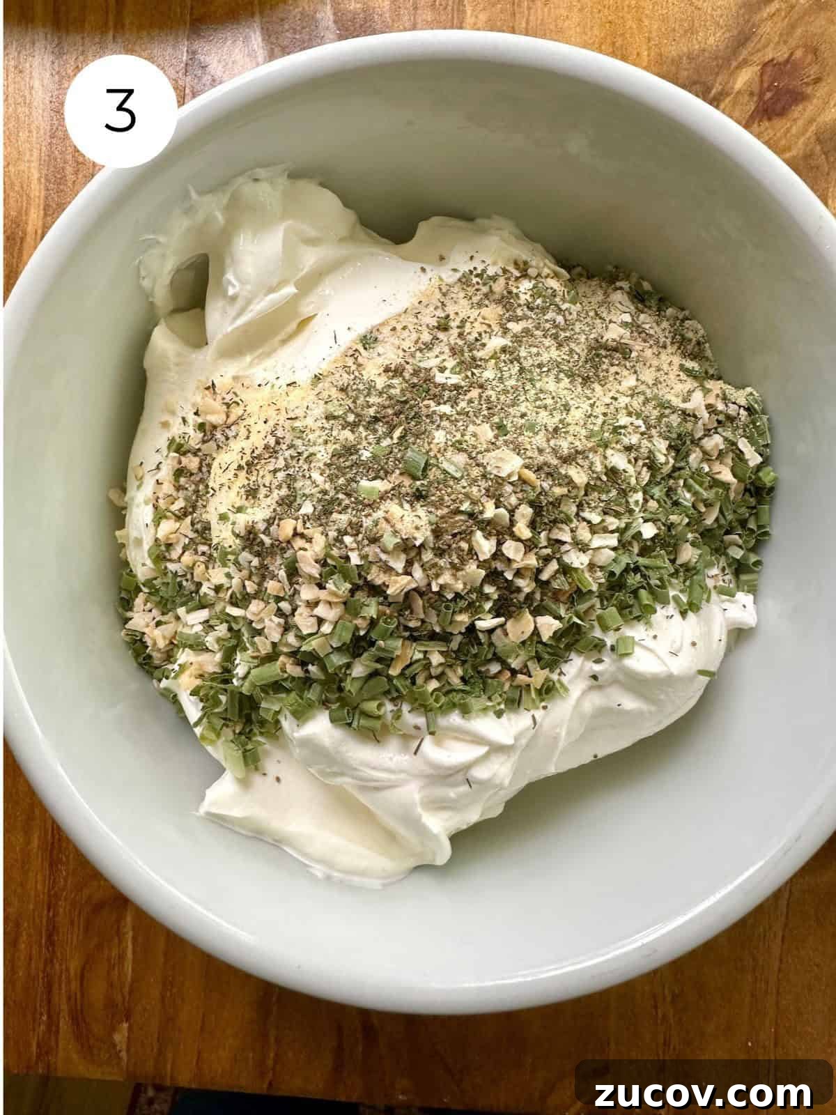 Creamy Herb and Garlic Dip Recipe for Parties and Snacks 6 Dried herbs on top of a sour cream in a bowl.