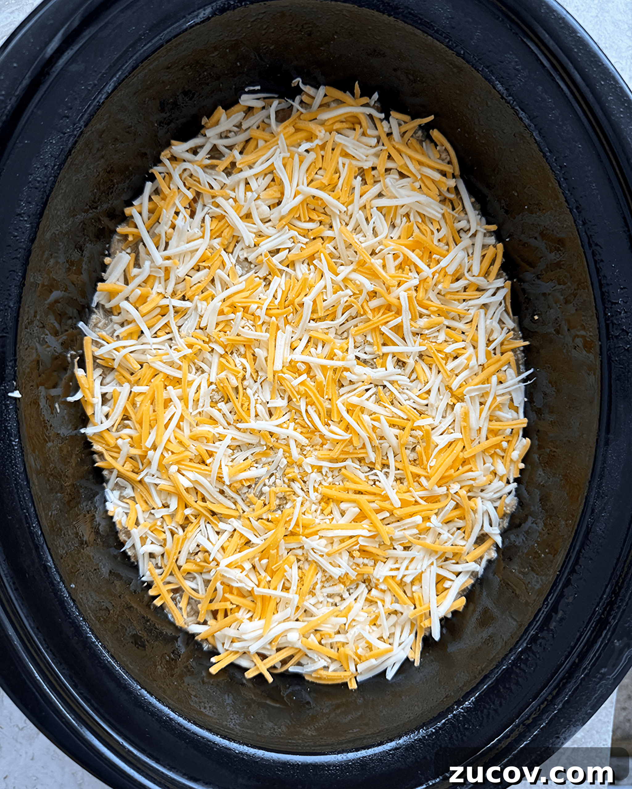 Salsa Verde Chicken Casserole (Slow Cooker Recipe) 3 overhead shot of uncooked salsa verde chicken casserole in a black slow cooker