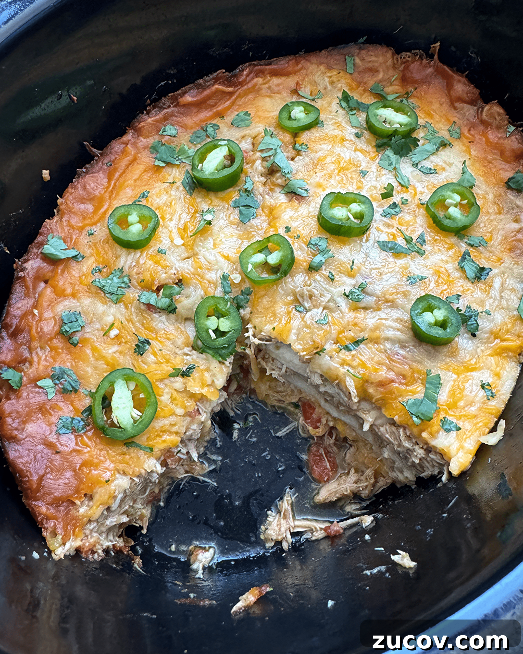 Salsa Verde Chicken Casserole (Slow Cooker Recipe) 6 overhead shot of salsa verde chicken casserole in a black slow cooker with a chunk cut out the middle