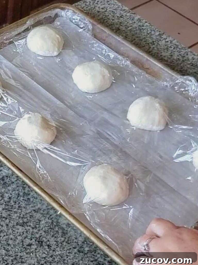 Crispy Gluten-Free French Rolls Recipe for Artisan Sandwiches 5 shaped rolls set on parchment-lined baking sheet and covering with plastic wrap.