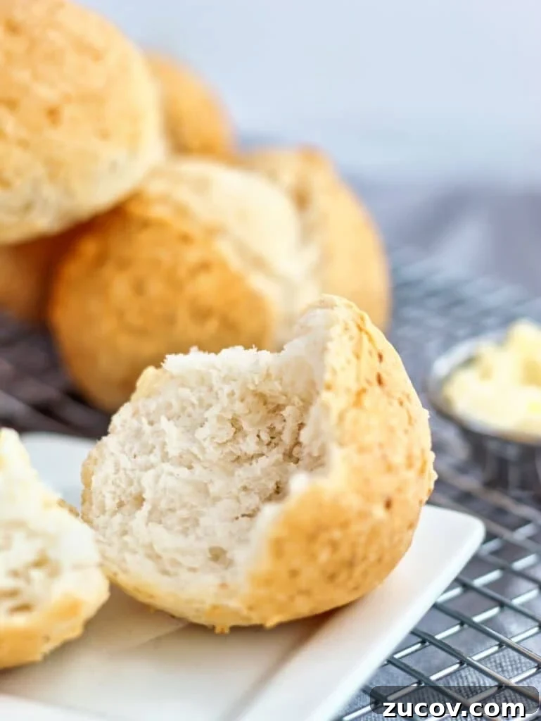 Crispy Gluten-Free French Rolls Recipe for Artisan Sandwiches 7 up close shot of split open roll on small white square plate with butter to the side.