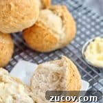 Crispy Gluten-Free French Rolls Recipe for Artisan Sandwiches 8 gluten free crusty french rolls on cooling rack with one roll split open on a small white square plate and butter to the side.