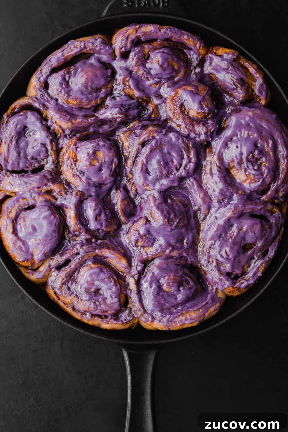 Cinnamon Rolls Made with Challah Dough: Soft, Buttery Recipe 2 Challah Dough cinnamon rolls with an ube cream cheese frosting all done and ready to be eaten! Overhead shot on a black background.