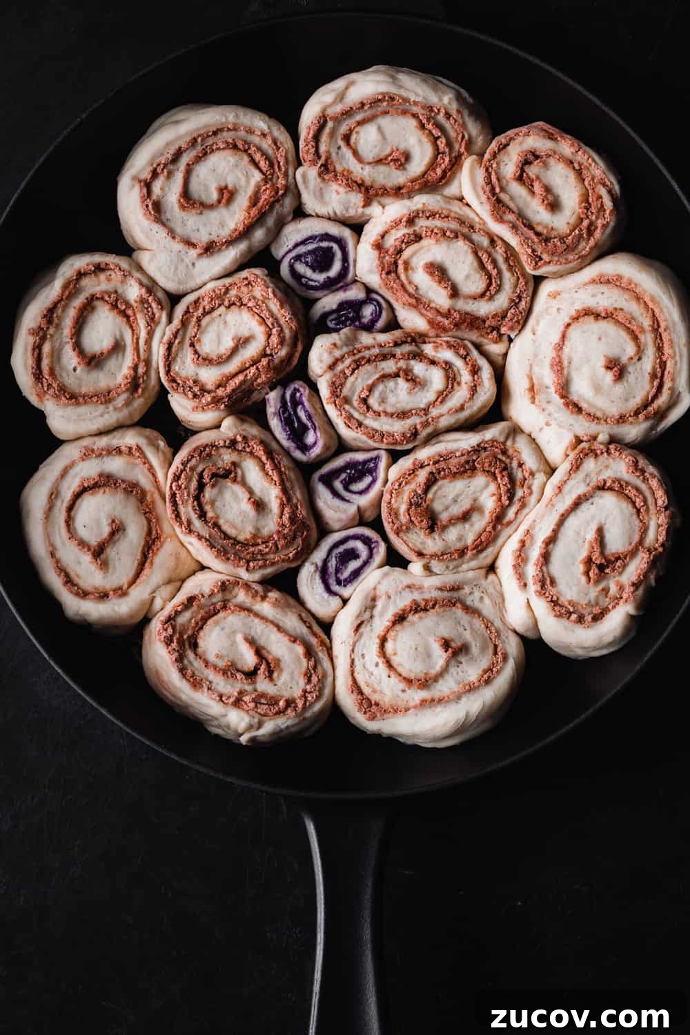 Cinnamon Rolls Made with Challah Dough: Soft, Buttery Recipe 3 Challah Cinnamon Rolls rising in a cast iron skillet; overhead shot on a black background.