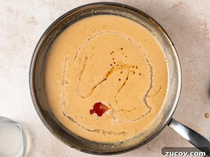 Adding sriracha, lime juice, and fish sauce to peanut sauce 