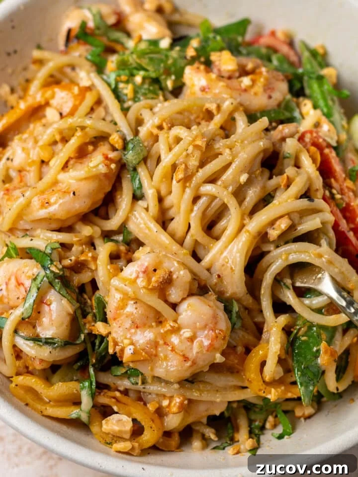 Close-up of creamy peanut noodles with shrimp, Thai basil, snap peas, and crushed peanuts