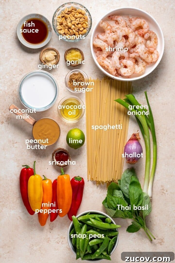 Ingredients for peanut noodles with shrimp including spaghetti, shrimp, peanut butter, coconut milk, snap peas, and Thai basil