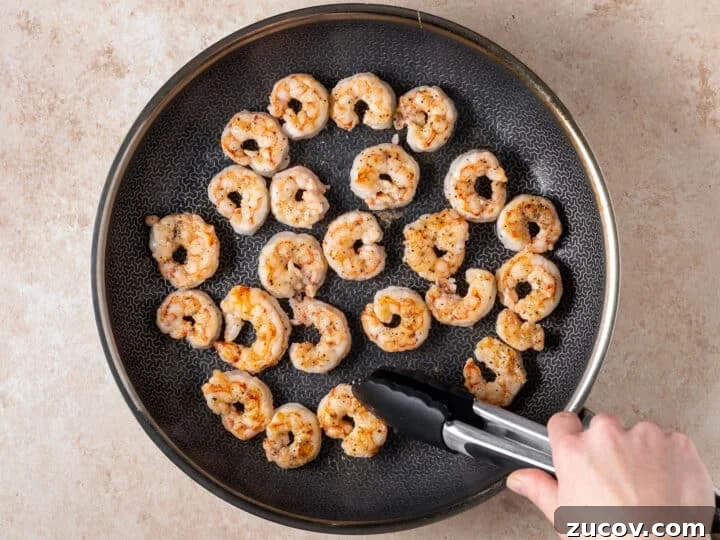 Seared shrimp cooking in a skillet for thai peanut noodles with shrimp