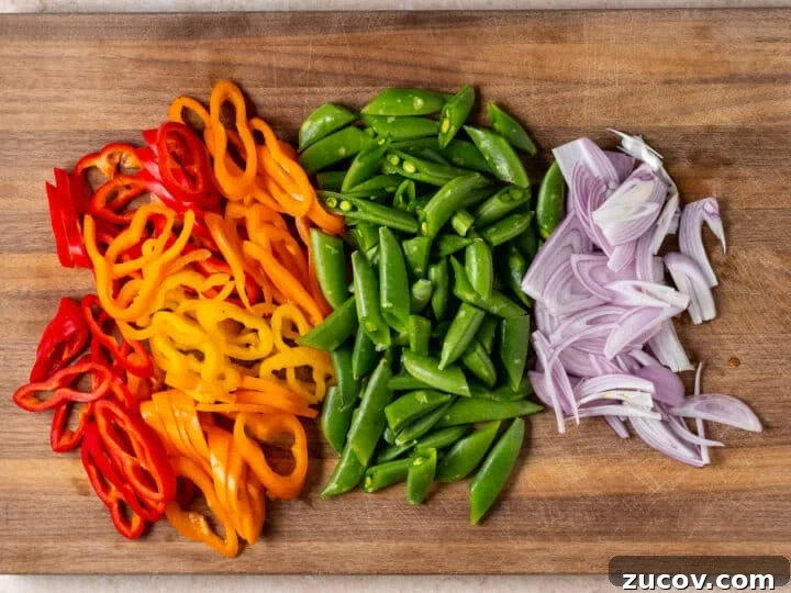 Sliced mini peppers, snap peas, and shallots prepared for peanut noodles with shrimp