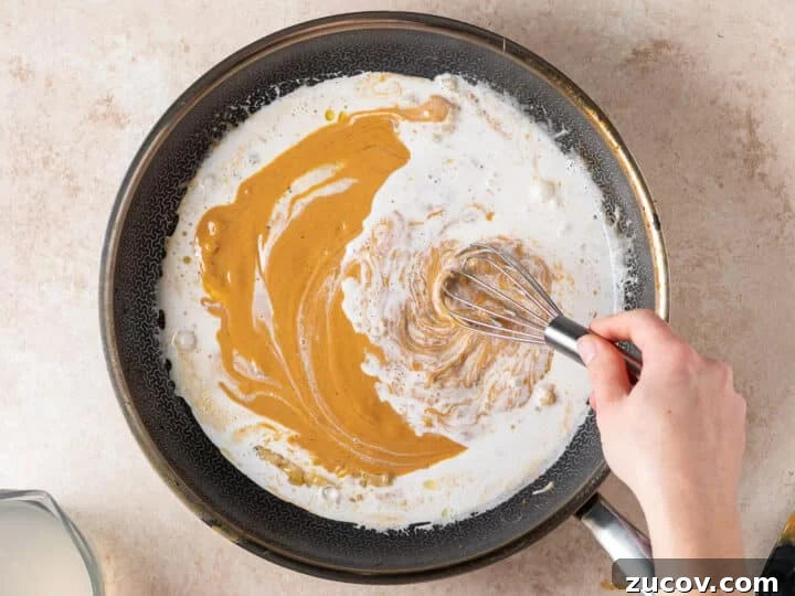 Whisking peanut butter into coconut milk for creamy peanut sauce