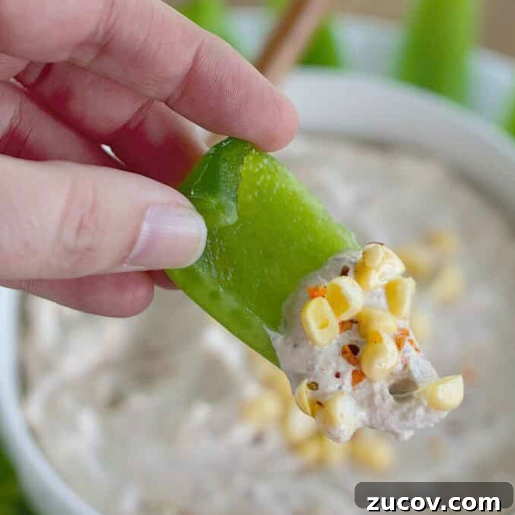 Creamy Chipotle Ranch Dip Recipe for Dipping & Spreading 3 hand holding piece of green bell pepper with chipotle ranch dip on it