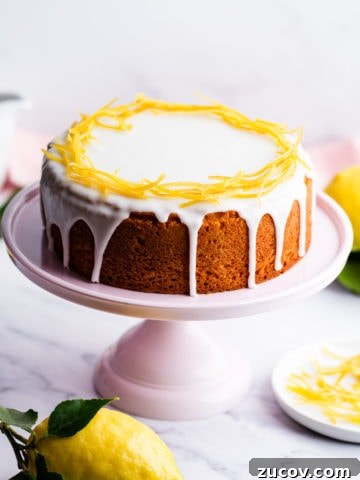 zesty lemon cake with icing and lemon peel decoration on a pink cake stand.