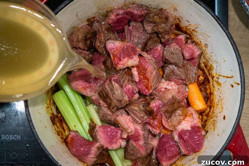 Classic Old-Fashioned Beef Stew Recipe (No Wine) 9 Pouring the chicken stock into the pot