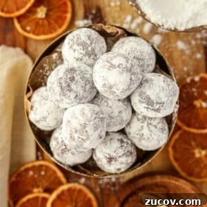 Decadent Chocolate Orange Truffles Recipe for Homemade Gifts 14 A bowl of chocolate truffles coated in powdered sugar, and surrounded by dried orange slices.