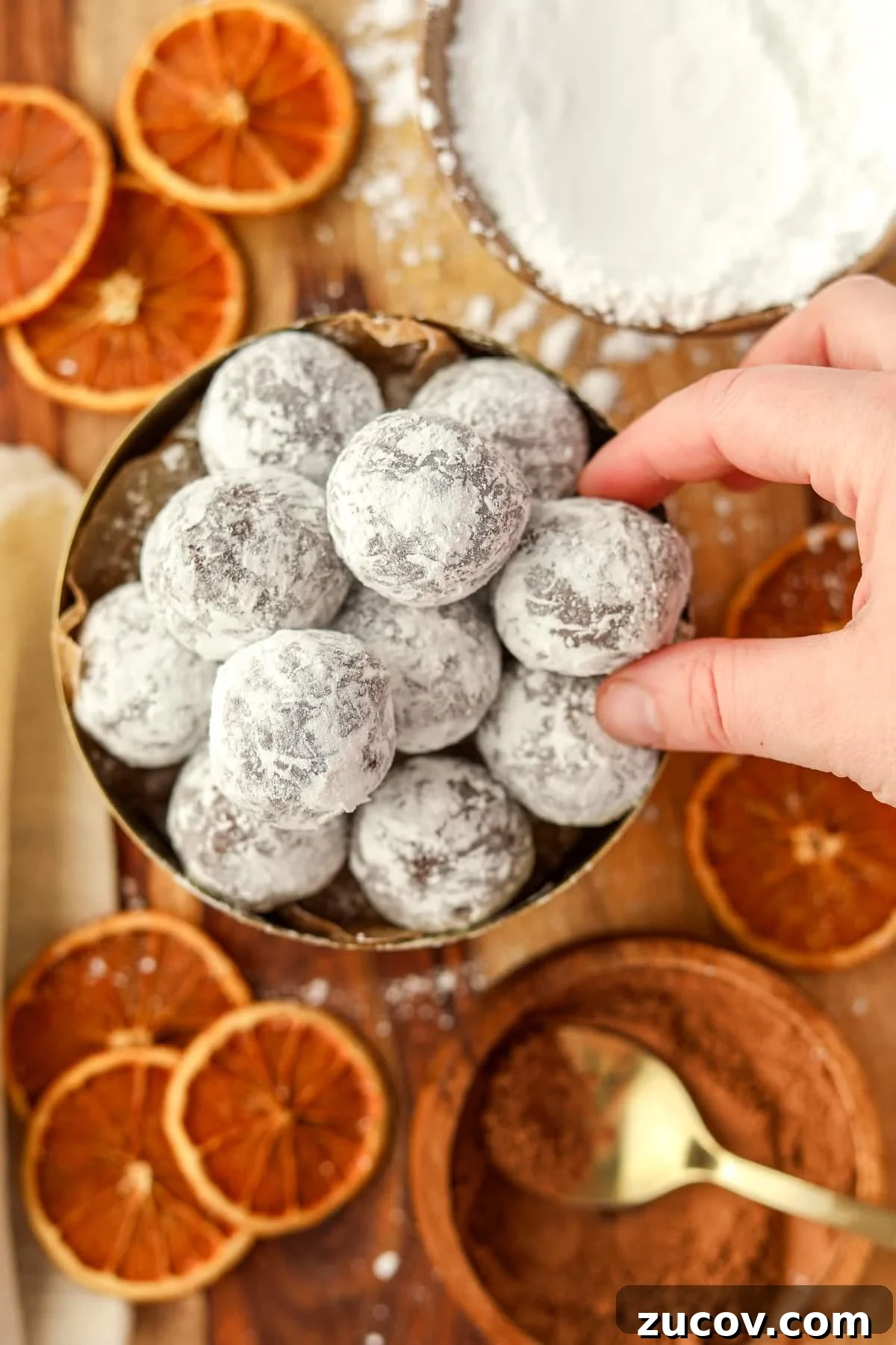 Decadent Chocolate Orange Truffles Recipe for Homemade Gifts 9 Picking a chocolate ball from a bowl of treats.
