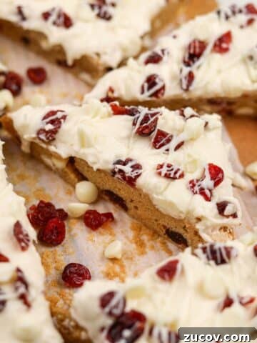 A triangular cranberry bliss bar topped with dried cranberries and cream cheese frosting.