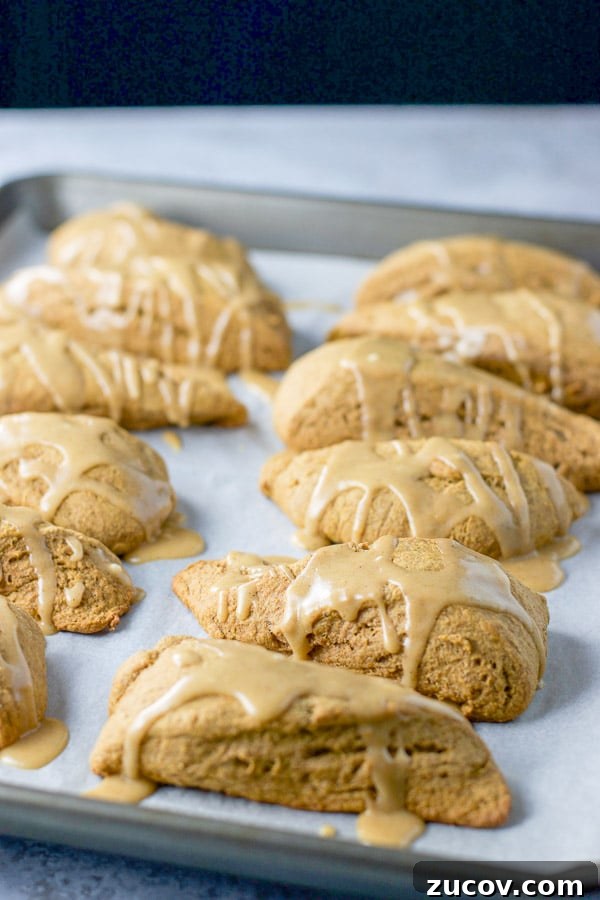 Pumpkin Glazed Scones with Maple Spice Frosting 2 A jelly roll pan covered with parchment paper with a bunch of glazed scones on it