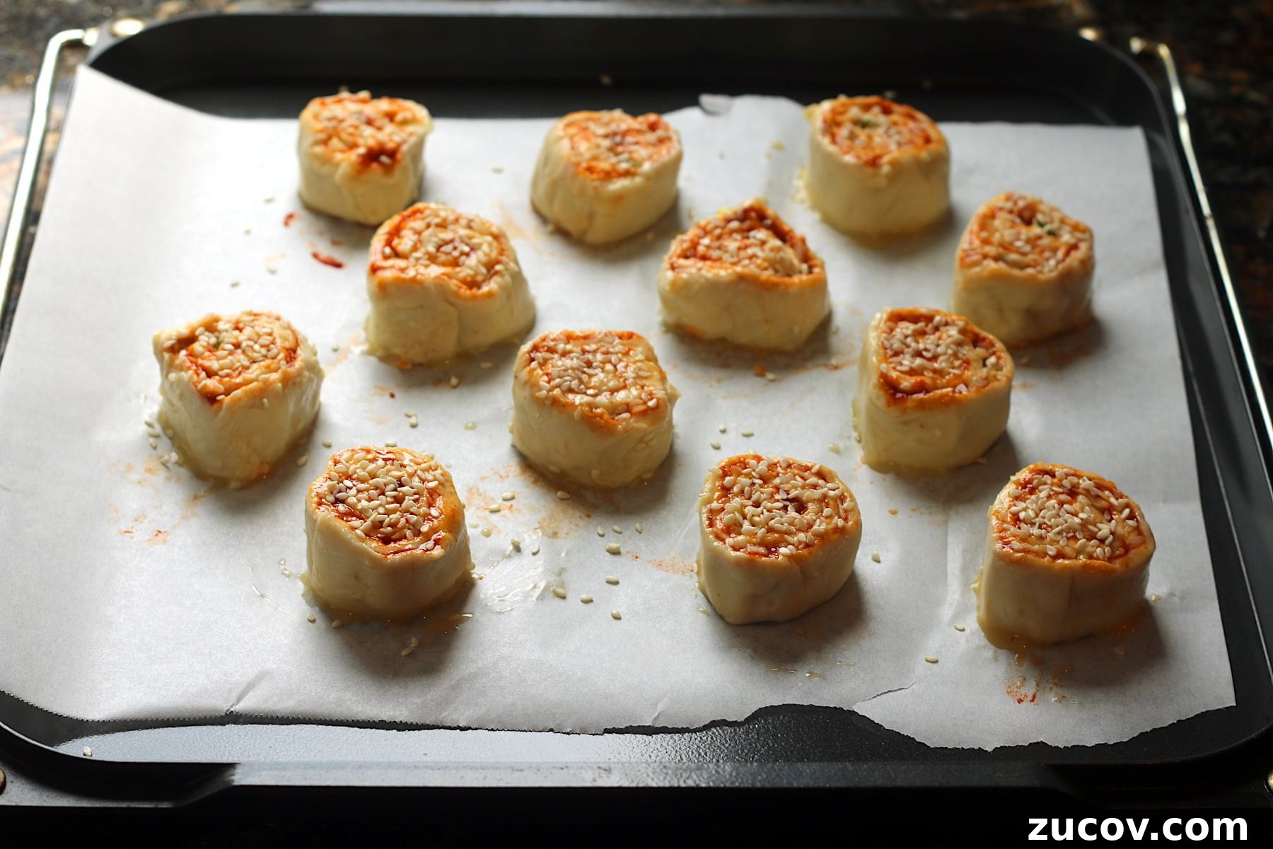 Gochujang Cheddar Pinwheel Appetizers: Spicy Korean Cheese Rolls 5 Gochujang cheddar pinwheels on a baking sheet before baking.
