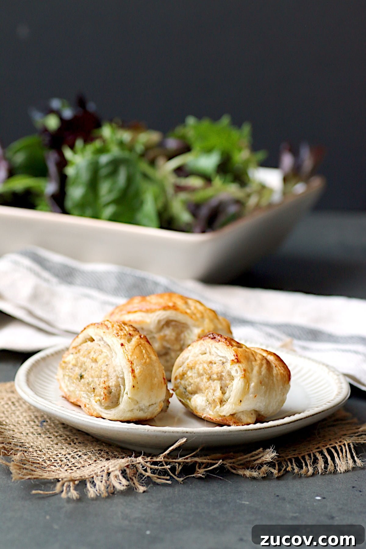 Gochujang Cheddar Pinwheel Appetizers: Spicy Korean Cheese Rolls 8 Small appetizer-sized sausage rolls on a white plate.