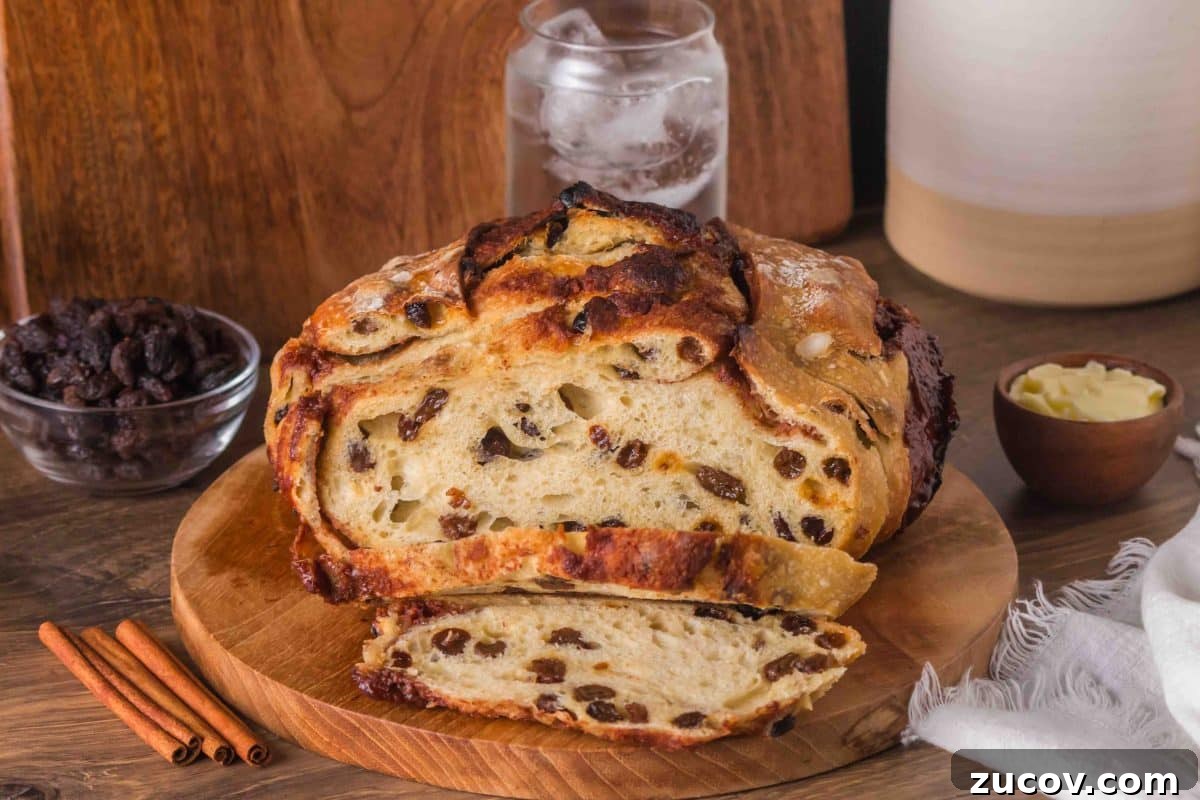 Sourdough Cinnamon Raisin Bread Recipe — Soft, Sweet & Spiced 2 Golden brown sourdough cinnamon raisin bread with visible raisins and cinnamon swirls, cooling on a cutting board. Hostess At Heart