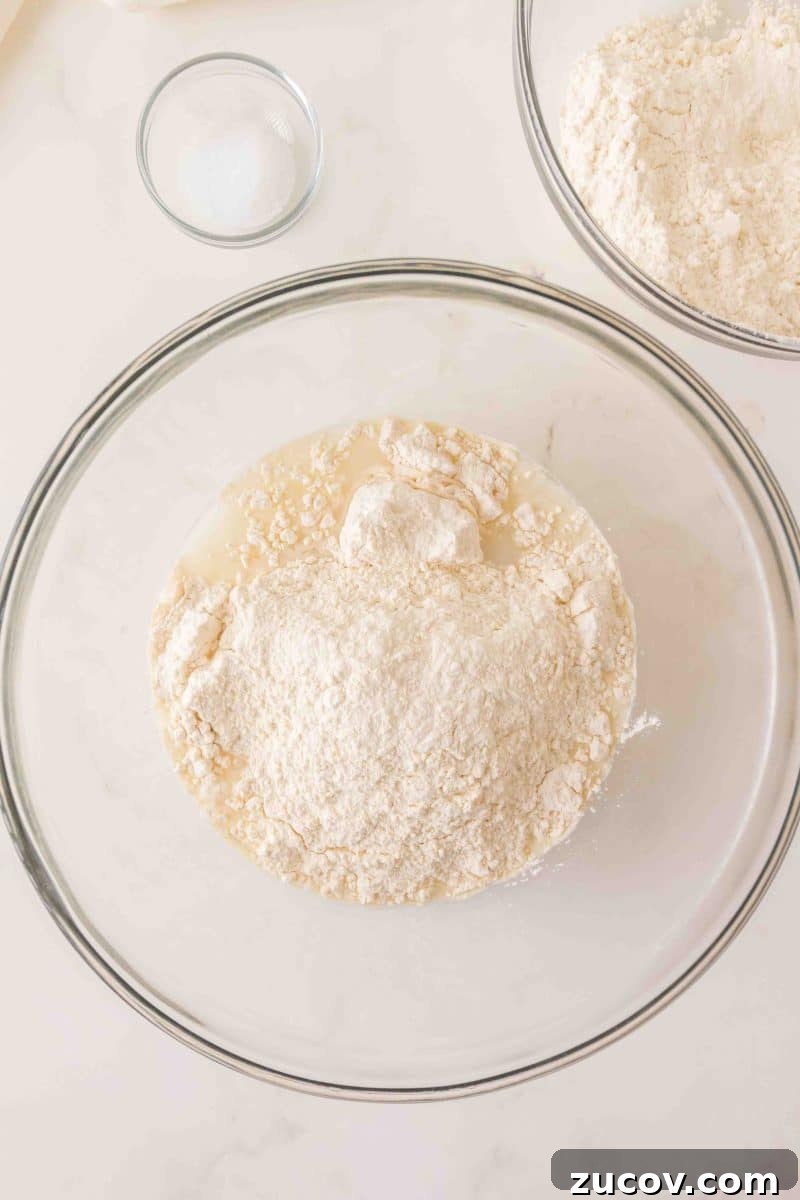 Sourdough Cinnamon Raisin Bread Recipe — Soft, Sweet & Spiced 5 Flour added to a milky mixture of water and sourdough starter in a mixing bowl. Hostess At Heart
