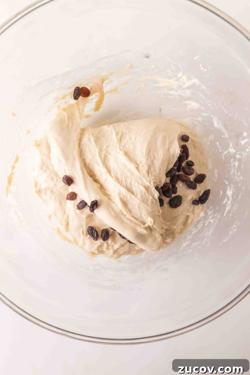 Sourdough Cinnamon Raisin Bread Recipe — Soft, Sweet & Spiced 8 Sticky sourdough bread dough in a mixing bowl with dark raisins folded throughout - Hostess At Heart